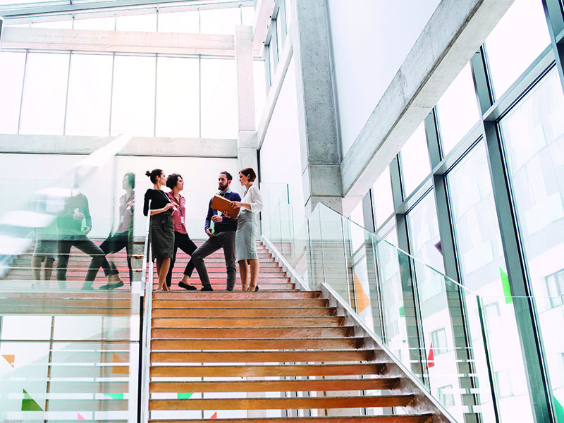 A group of CPAs in discussion at the top of the stairs in an office building