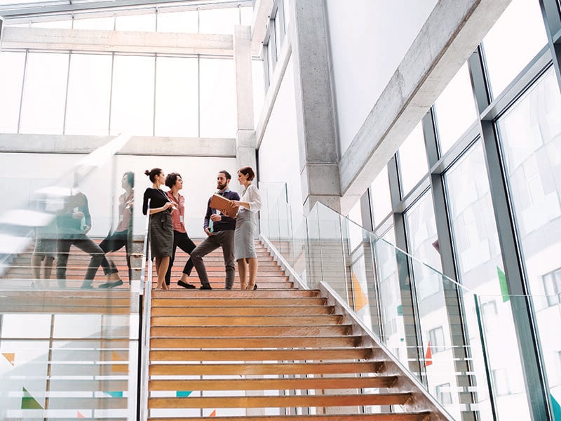 A group of CPAs in discussion at the top of the stairs in an office building